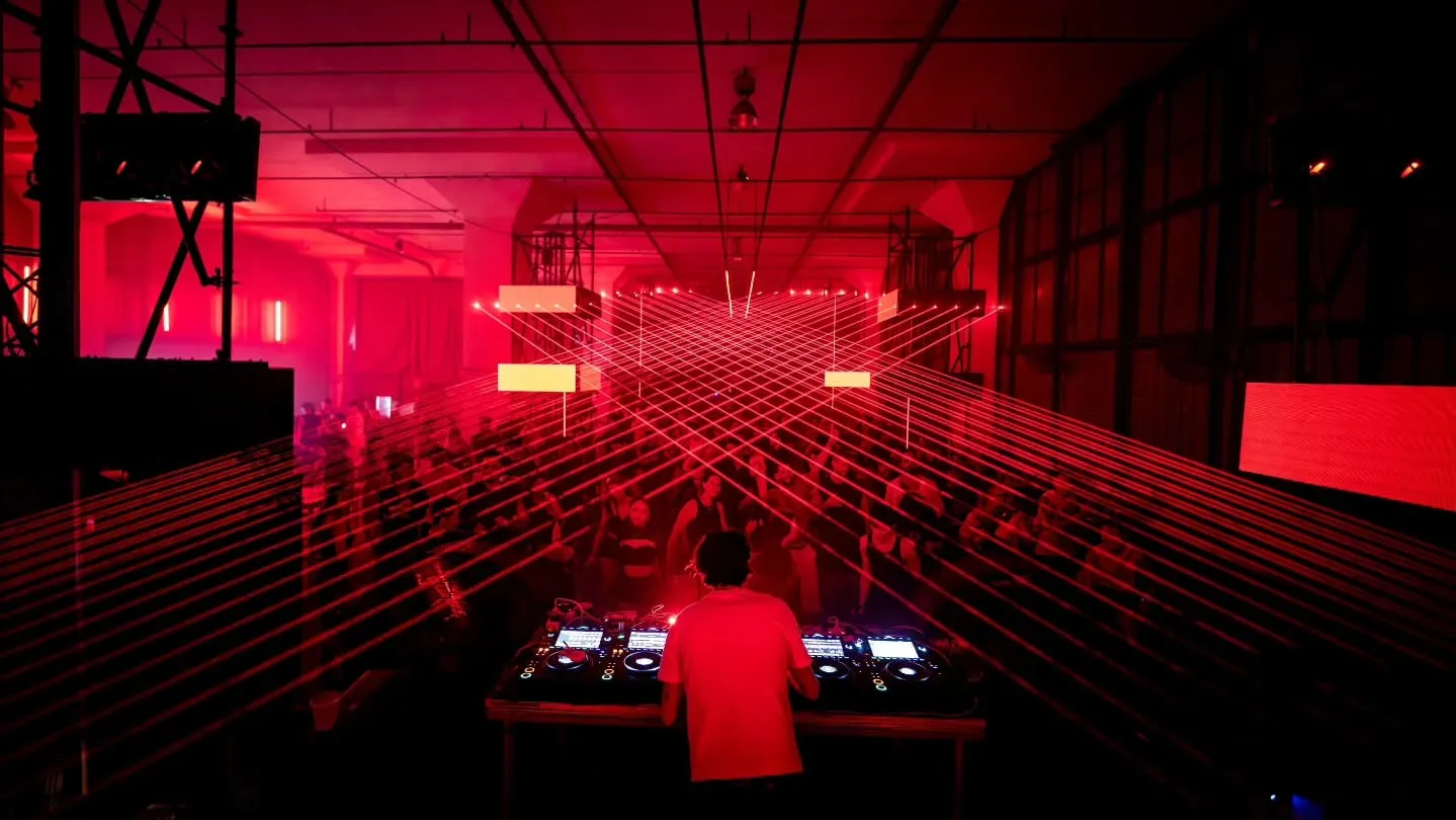 From behind the booth, the laser grid running the length of the warehouse over the crowd