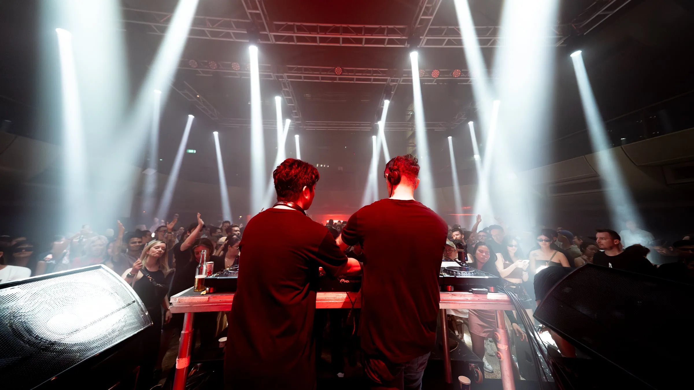 Two DJs from behind the booth, beams fanning out over the crowd