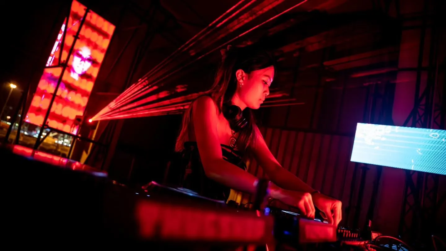 The DJ at the decks with the panels lit behind